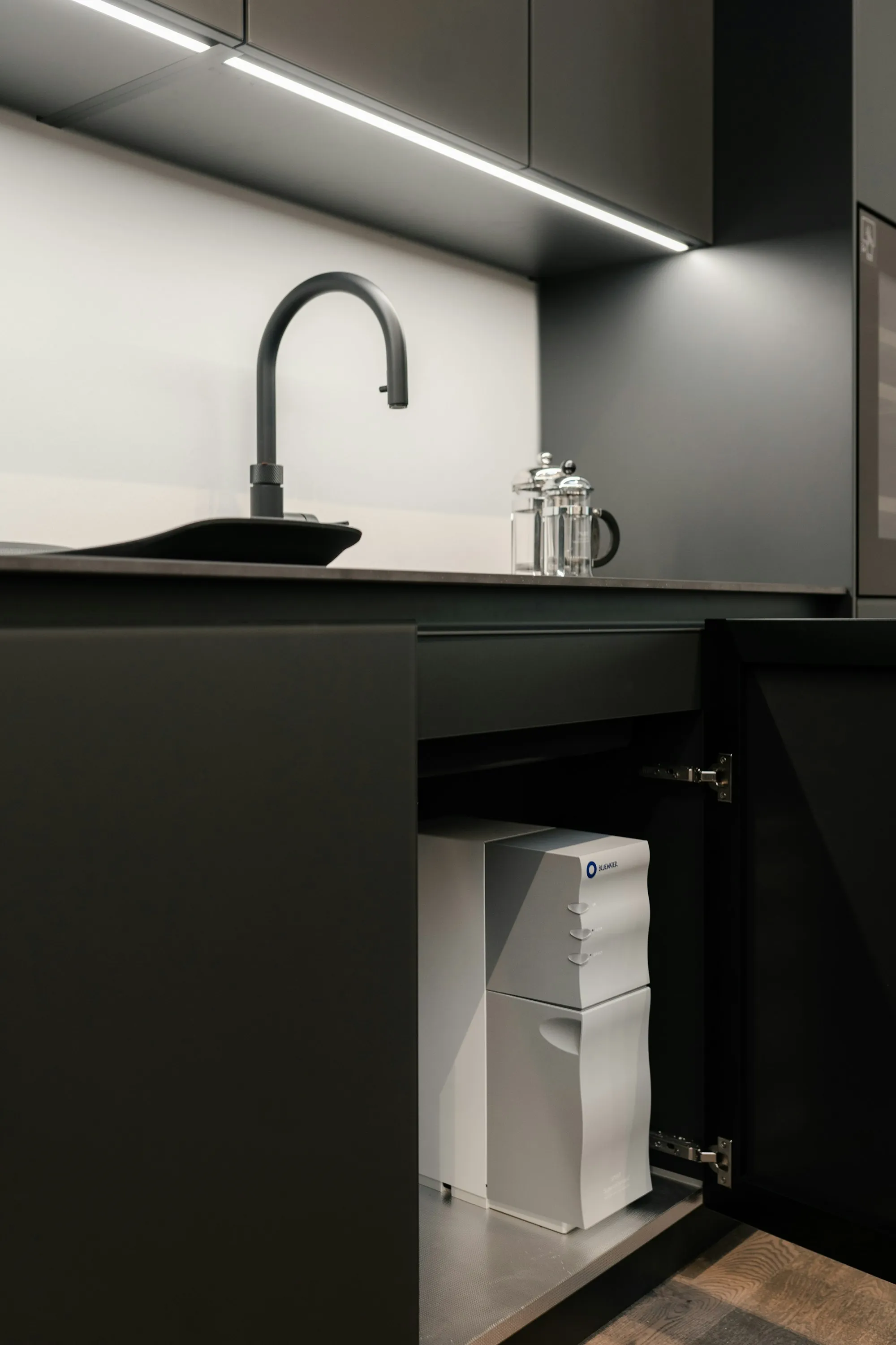 Black kitchen faucet over a sink with cabinets below