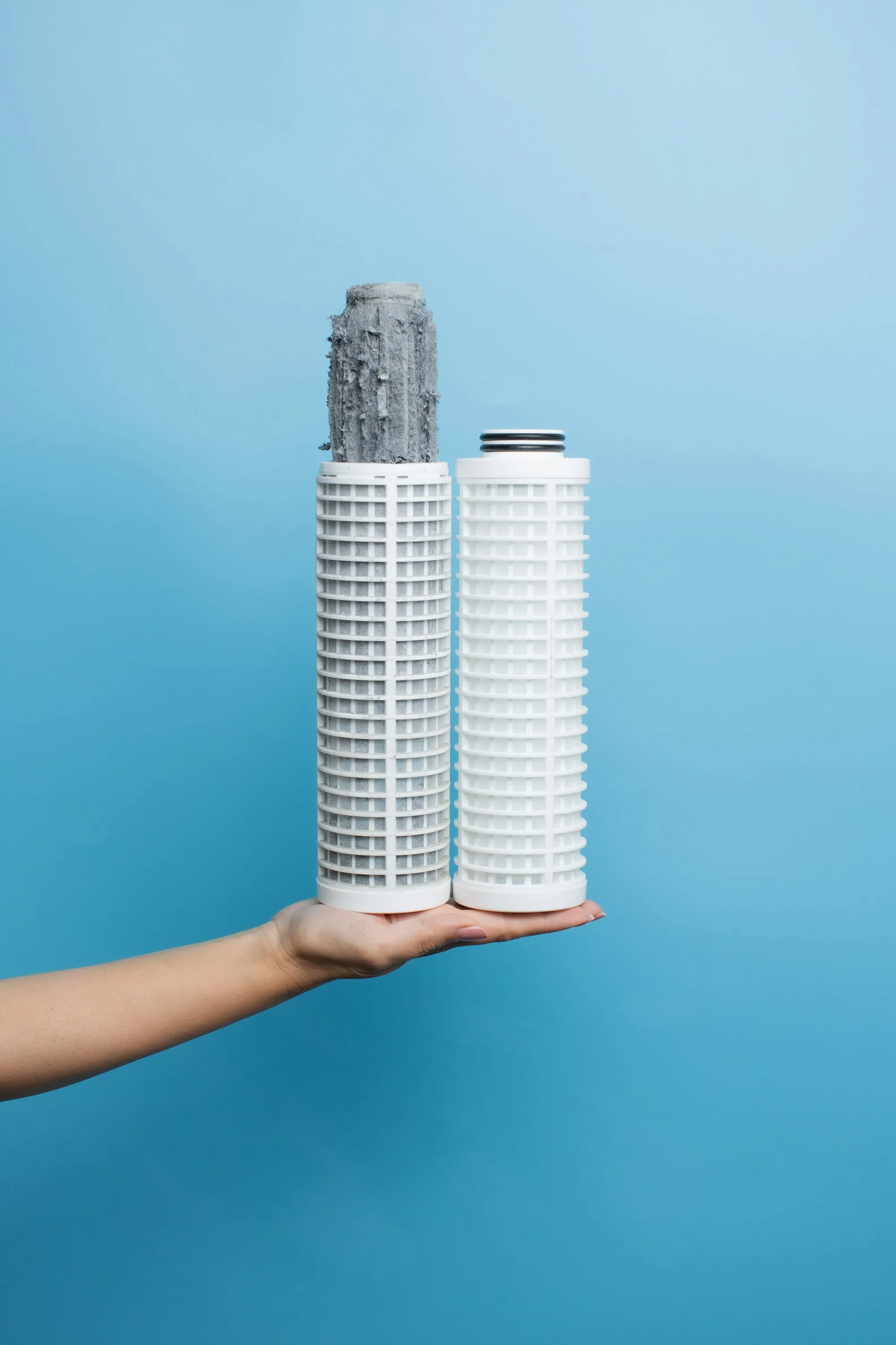 Hand holding two replacement water filter cartridges